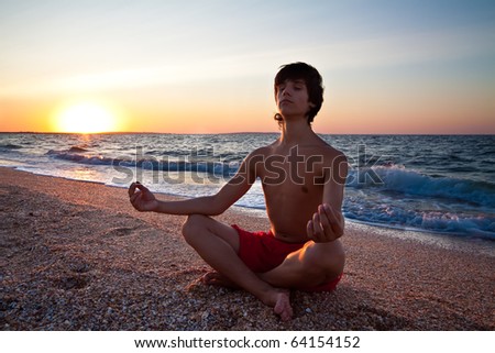 stock photo Teen boy at the beach meditating on sunset