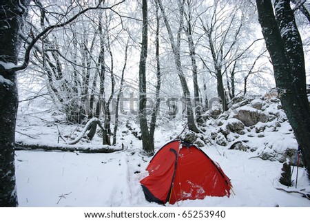 Red tourist tent in winter forest