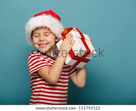 Smiling  funny child in Santa red hat holding Christmas gift in hand. Christmas concept.