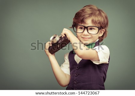 Cheerful  smiling  child (boy) holding a instant camera