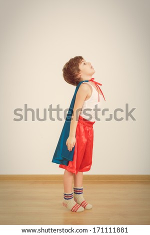 Funny little power super hero child (boy) in a blue raincoat.  Superhero concept