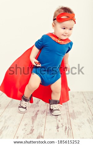 Funny little power super hero child (boy) in a blue raincoat. Superhero concept