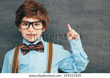 Cheerful smiling little kid (boy) against  chalkboard. Looking at camera. School concept
