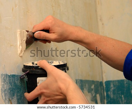 human arm(hand) repairs a wall (focus on right hand)