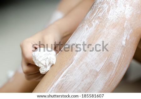 Body hygiene: Woman depilates - scrubs hair removal cream off her leg