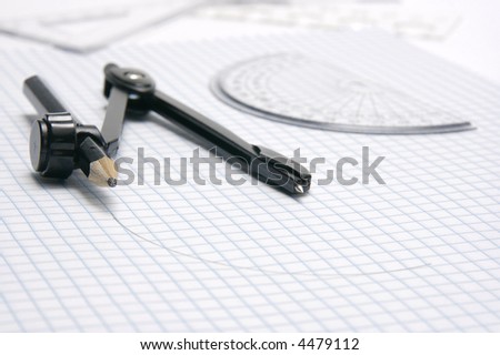 Compass, protractor and rulers, with drawn semi-circle, on blue lined graph paper