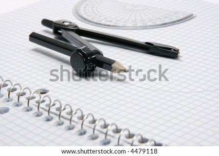 Compass and protractor with drawn semi-circle sitting on graph paper book with coil binding.