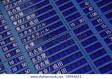 Airport display board with Japanese characters and flight times.