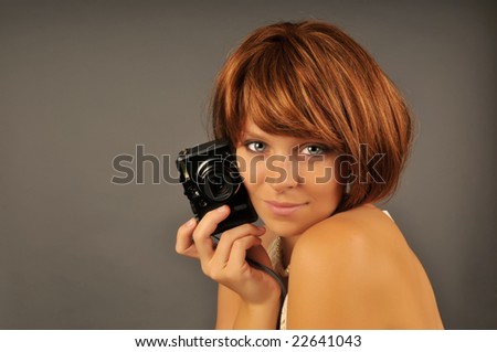 Portrait of beautiful woman with red hair holding a camera looking over shoulder.