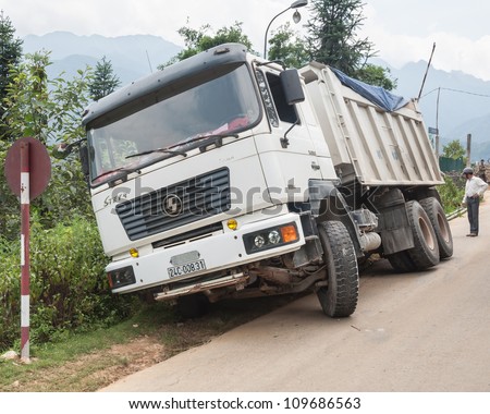 SAPA, VIETNAM - AUGUST 05: Truck that slid from the road on August 05, 2012 not far from Sapa, Vietnam. A driver is evaluating a possibility of rescuing it from sliding farther.