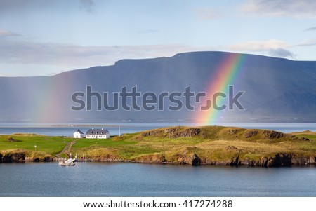 Reykjavik Landscape.  The view from Reykjavik harbour in Iceland as rain falls and a rainbow forms.  In the background is the Esja volcanic mountain range.