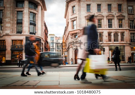 Anonymous motion blurred shopping couples carrying shopping bags on Regent Street, London.