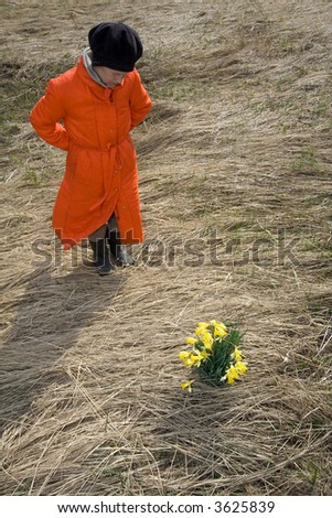 Woman stand at field of dry herbage in front of yellows narcissi