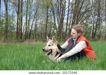 Woman sitting with alsatian dog on grass at nature