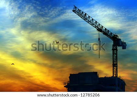 Beautiful sky at sunrise in city. Building under construction and crane. Also two flying birds.