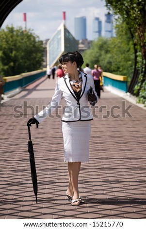 Young woman from high society walking at sunny day in city.