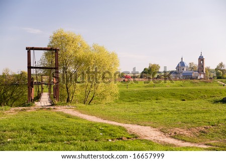 Rural scene: At first plane pendant bridge, at background church and several country houses.