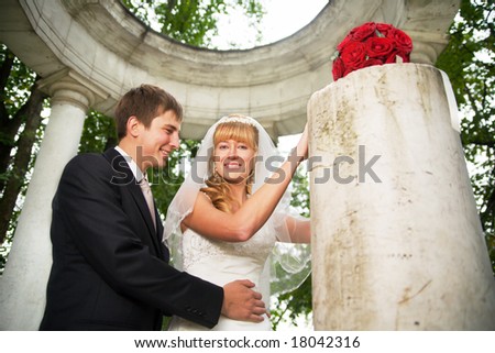 the newly married couple smiling at some old classic style pavilion