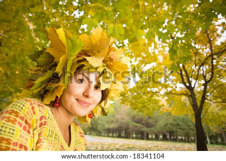 Young beautiful woman with crown of maple leaves in autumn park
