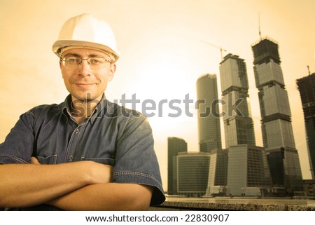 The architect wearing a protective helmet standing in front of a building site