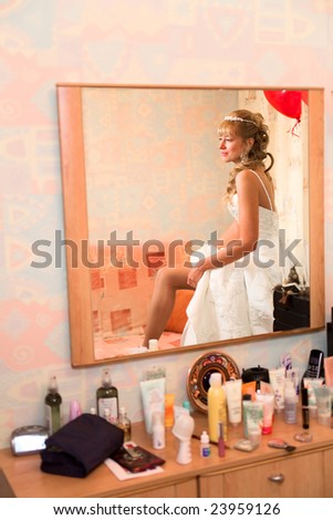 Reflection of bride get dressed in mirror