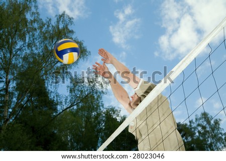 One young man is throwing the ball above the net