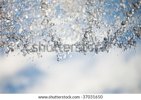 Water droplets on sunlight and sky with clouds at background.