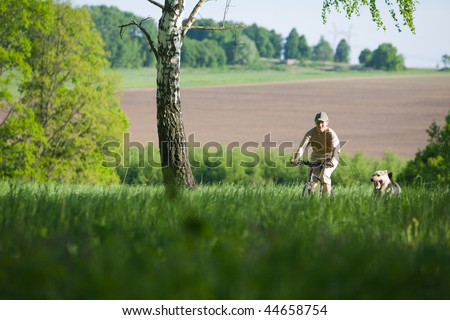 50 years old woman at bicycle with alsatian dog