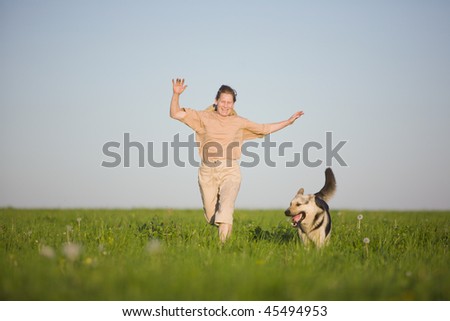 50 years old woman running with dog at  summer field