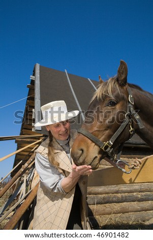 Mature adult woman feeding  her horse at farm