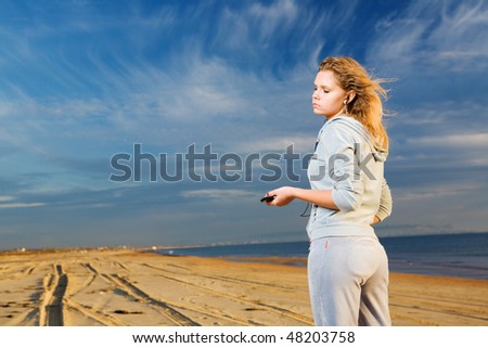 Young woman listen music with closed eyes at sunny day at seashore