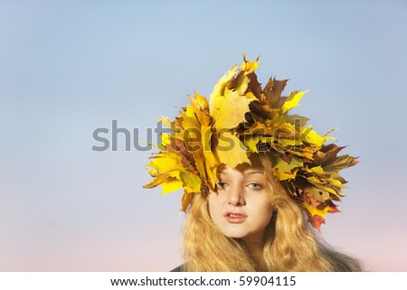 Young beautiful woman with crown of maple leaves in autumn