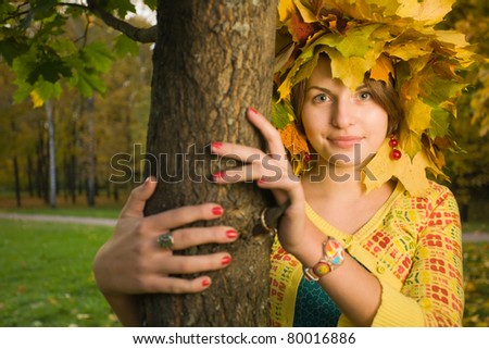 Young beautiful homely woman with crown of maple leaves in autumn park