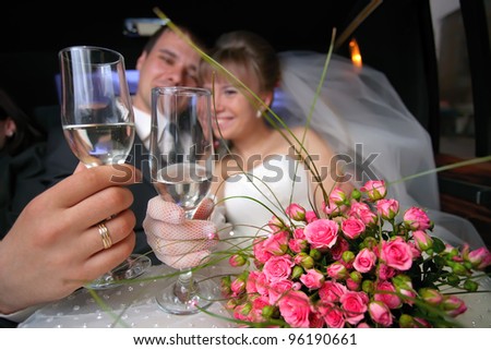 Wedding glasses with just married couple in limousine as a background