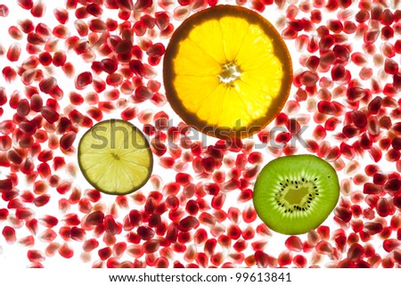 Pomegranate background on white with snack of orange, lime and kiwi