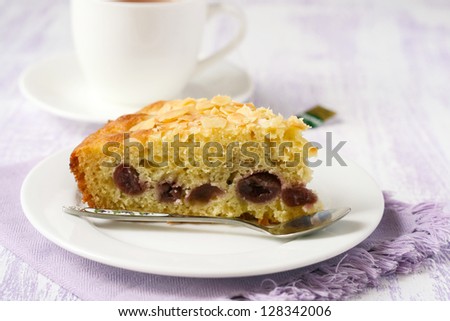 Slice of Cherry Almond coffee cake and cup of tea on the background