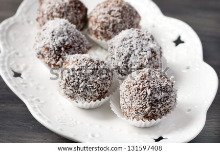 Homemade date candies covered with chocolate and shredded coconut