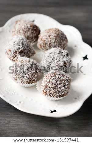 Homemade date candies covered with chocolate and shredded coconut