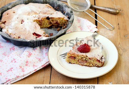 Slice of strawberry cake on the plate and the cake in the tin