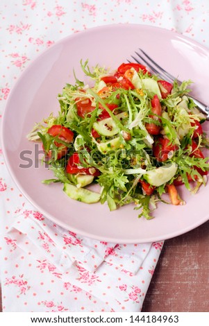 Salad: cucumbers, tomatoes, salad leaves with dressing on plate