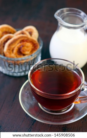 Cup of tea, milk in a jar and jam roll biscuits