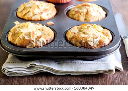 Muffins with almond on top in the baking tin, selective focus