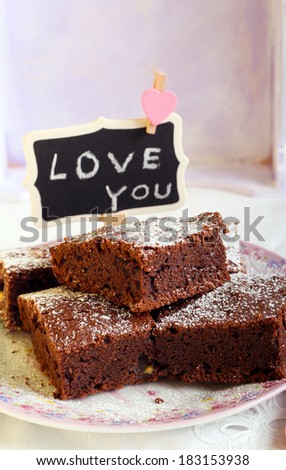 Chocolate brownies dusted with icing sugar on plate and a sign saying Love You