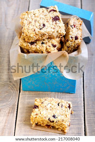 Oat bars with cranberry, nuts and seeds in a box, selective focus on the top slice