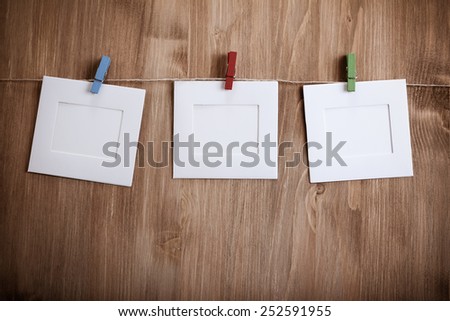 hanging empty photo frames, over wooden background