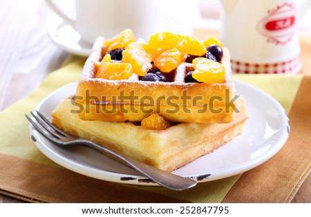 Waffles with fruits and berries under icing powder
