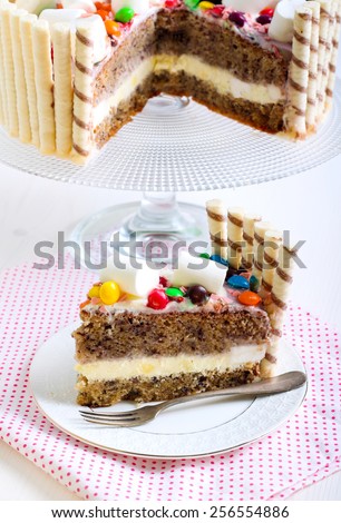 Banana layered cake with cream and yogurt filling, decorated with candies and marshmallows