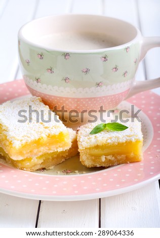 Tangy lemon squares with icing sugar and cup of coffee
