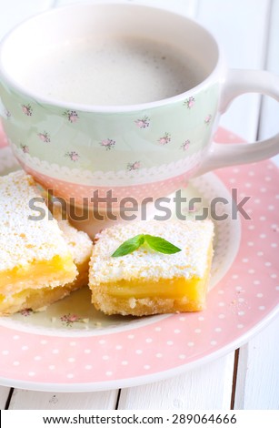 Tangy lemon squares with icing sugar and cup of coffee