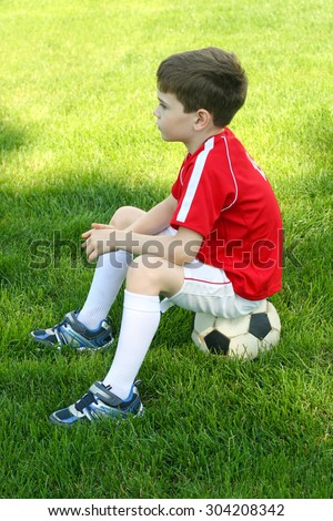 boy sitting on a soccer ball in the park